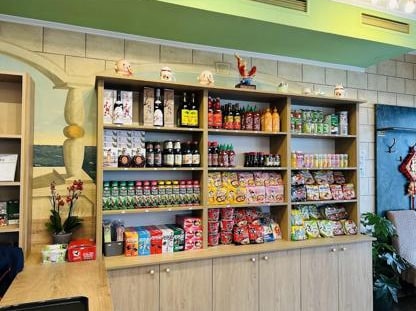 Holzregal im Lokal mit asiatischen Saucen, Instant-Nudeln und Snacks